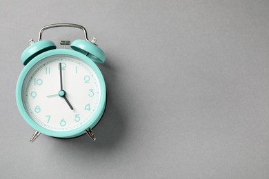 Photo of One turquoise alarm clock on light grey background, top view. Space for text
