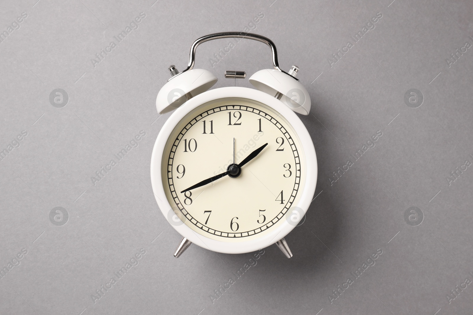 Photo of One white alarm clock on light grey background, top view