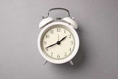Photo of One white alarm clock on light grey background, top view