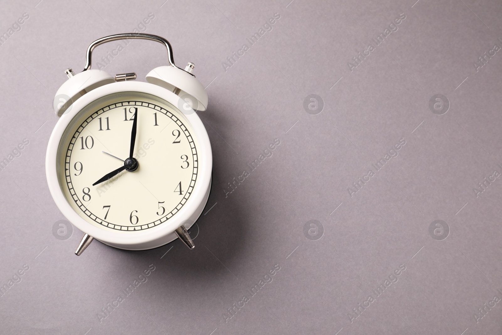 Photo of One white alarm clock on light grey background, top view. Space for text