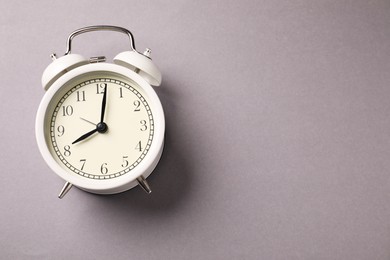 Photo of One white alarm clock on light grey background, top view. Space for text