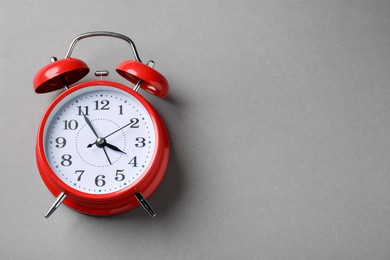 Photo of One red alarm clock on light grey background, top view. Space for text