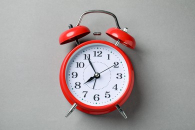 Photo of One red alarm clock on light grey background, top view