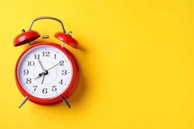 Photo of Red alarm clock on yellow background, top view. Space for text