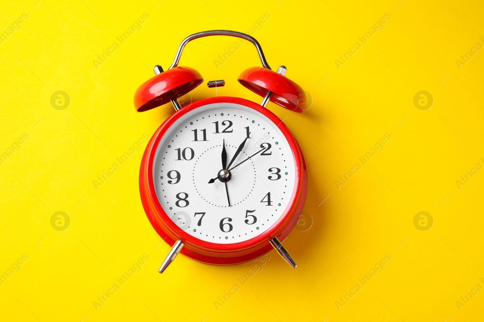 Red alarm clock on yellow background, top view Photo of Red alarm clock on yellow background, top view