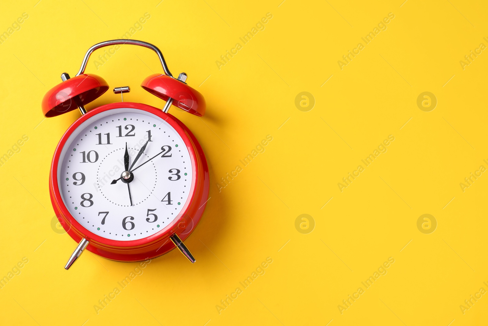 Red alarm clock on yellow background, top view. Space for text Photo of Red alarm clock on yellow background, top view. Space for text