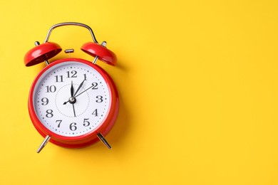 Photo of Red alarm clock on yellow background, top view. Space for text