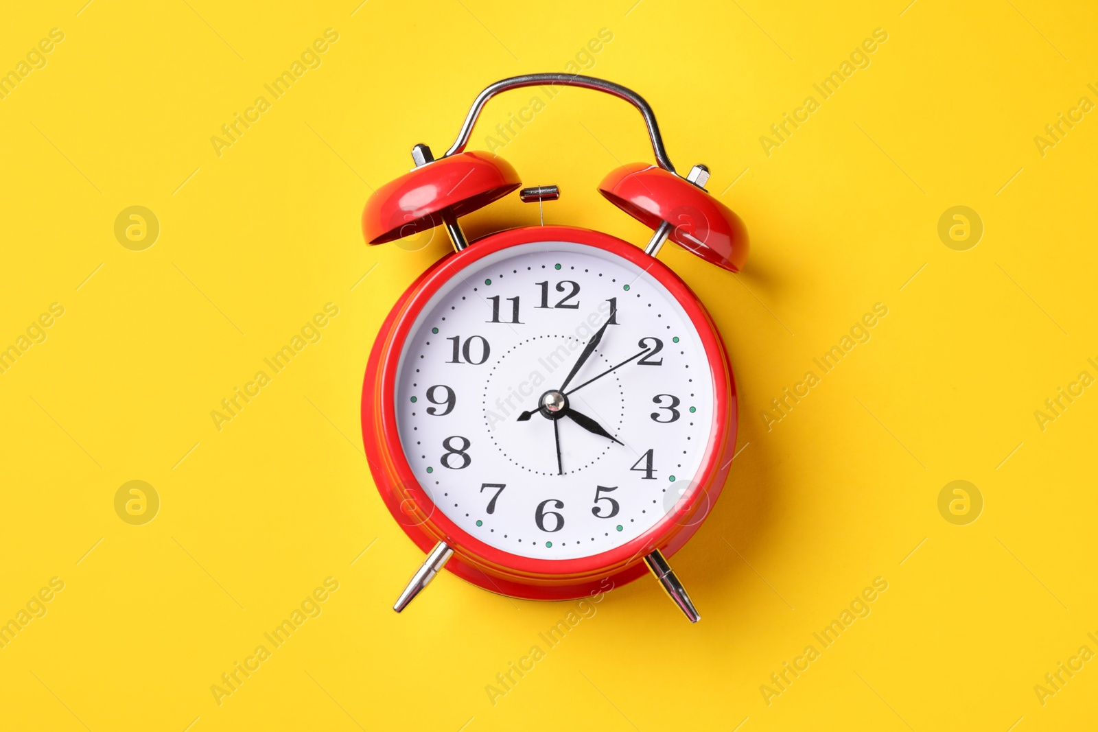 Red alarm clock on yellow background, top view Photo of Red alarm clock on yellow background, top view