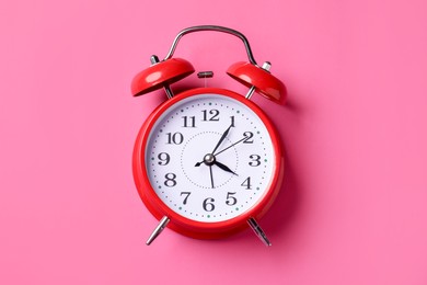 Photo of Red alarm clock on pink background, top view