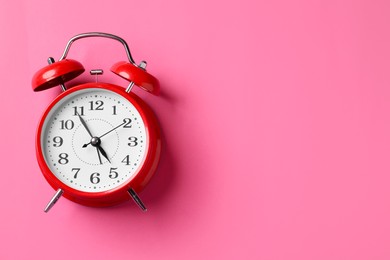 Photo of Red alarm clock on pink background, top view. Space for text