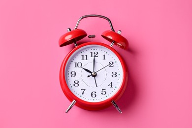 Photo of Red alarm clock on pink background, top view