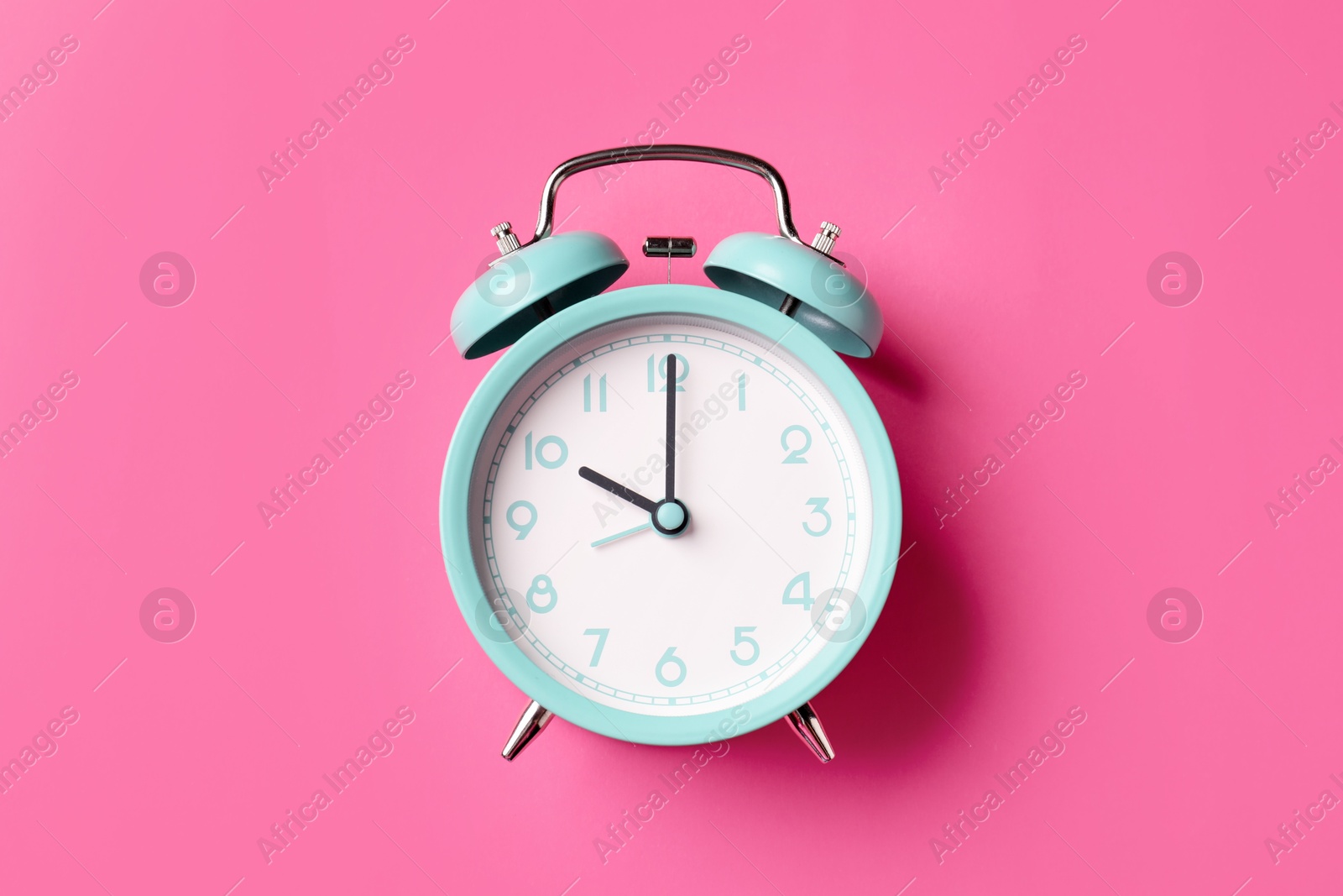 Turquoise alarm clock on pink background, top view Photo of Turquoise alarm clock on pink background, top view