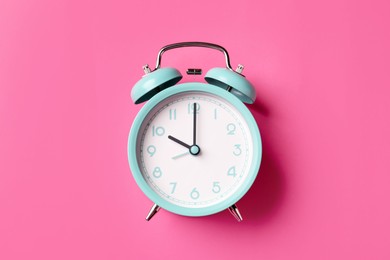 Photo of Turquoise alarm clock on pink background, top view