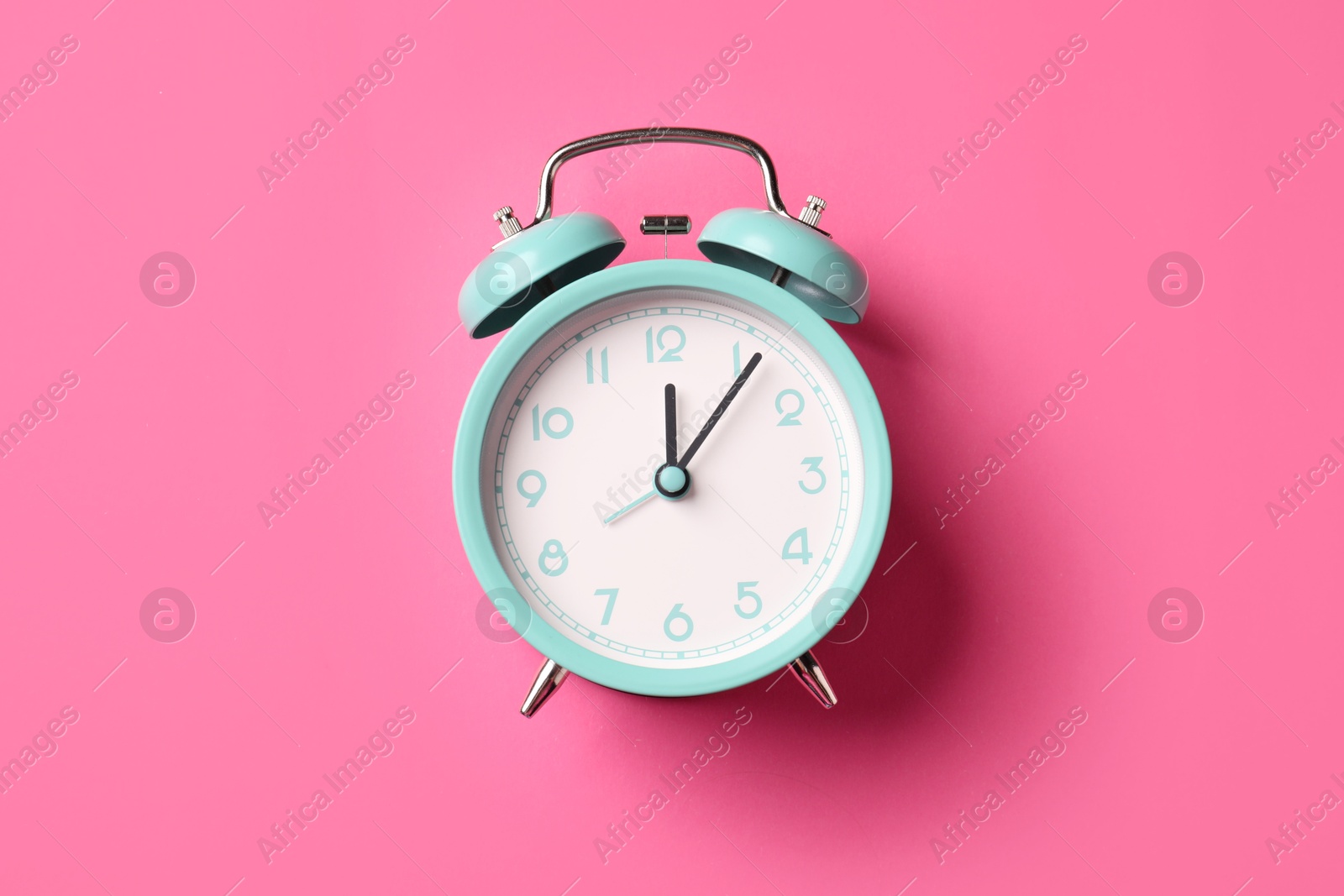 Turquoise alarm clock on pink background, top view Photo of Turquoise alarm clock on pink background, top view