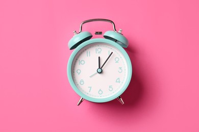 Photo of Turquoise alarm clock on pink background, top view