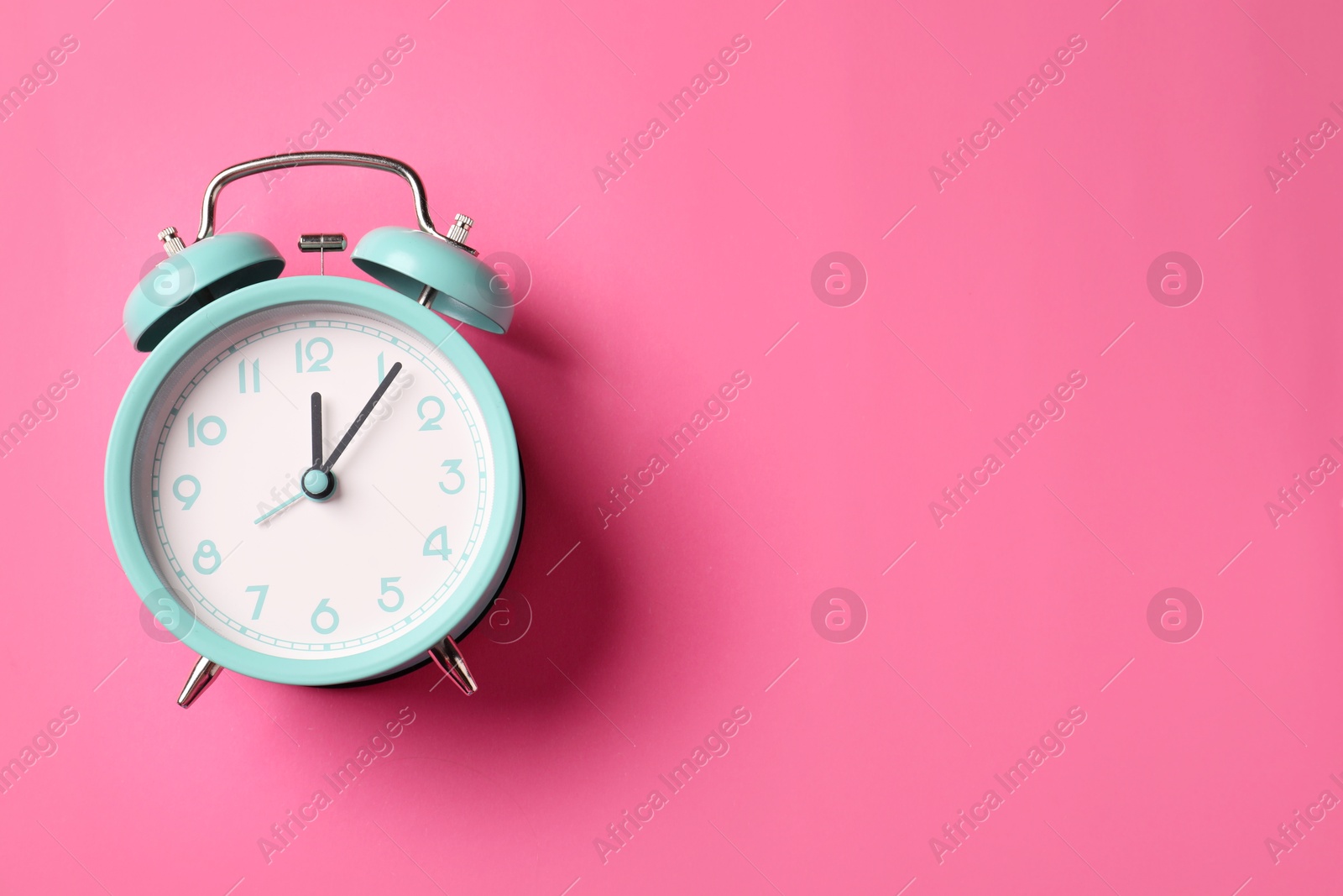 Turquoise alarm clock on pink background, top view. Space for text Photo of Turquoise alarm clock on pink background, top view. Space for text