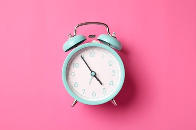 Photo of Turquoise alarm clock on pink background, top view