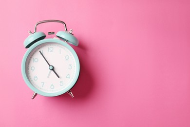 Photo of Turquoise alarm clock on pink background, top view. Space for text