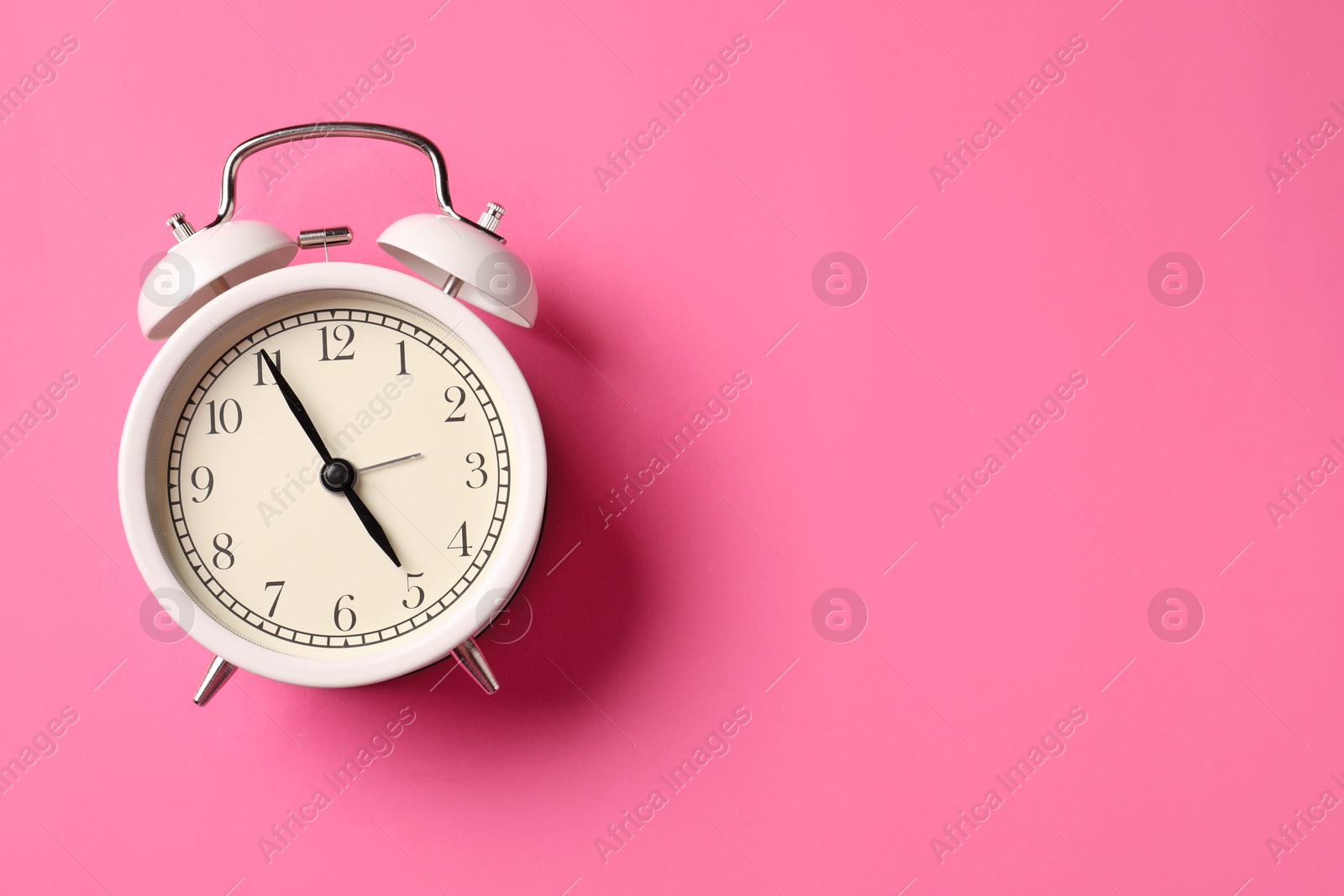 White alarm clock on pink background, top view. Space for text Photo of White alarm clock on pink background, top view. Space for text