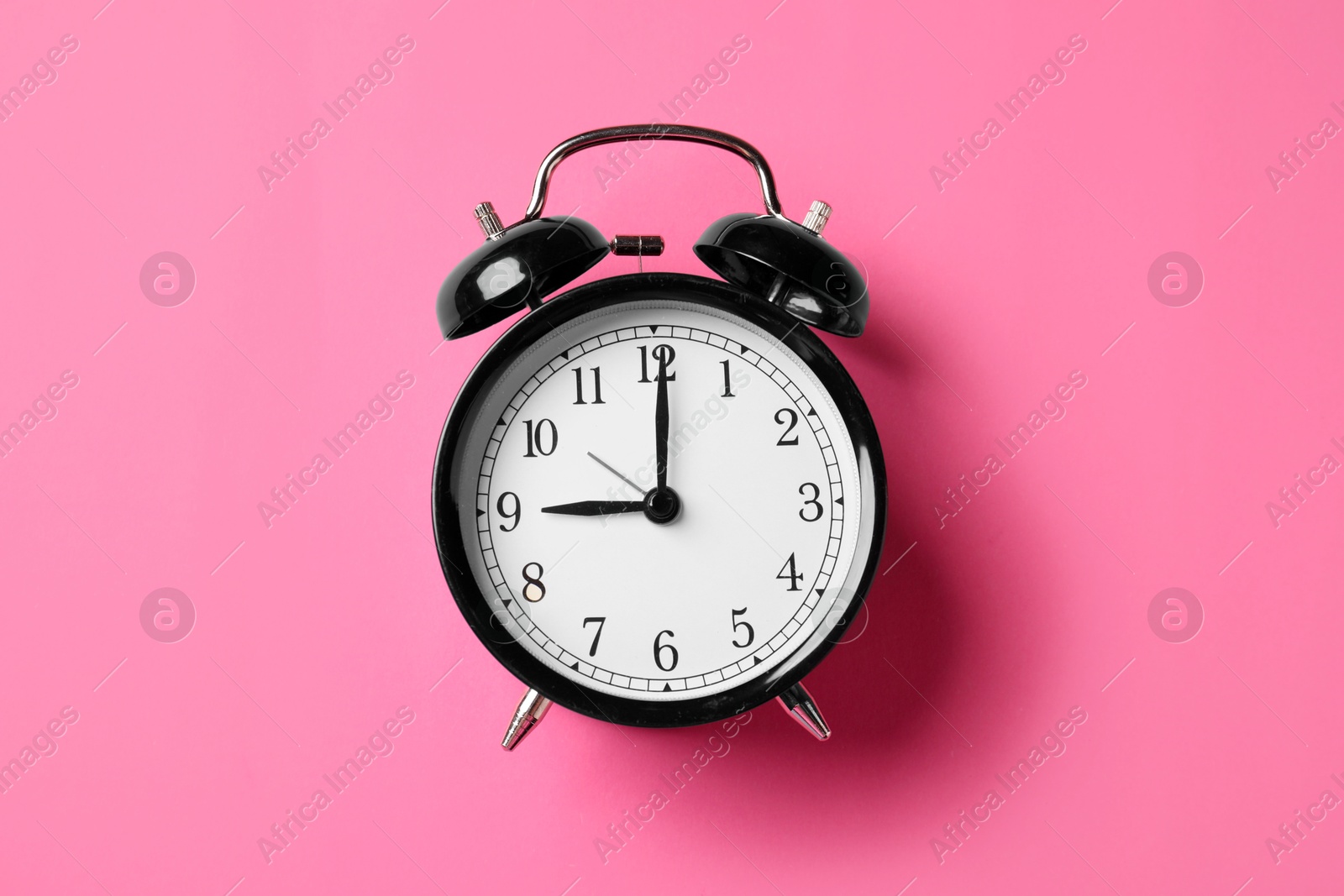 Black alarm clock on pink background, top view Photo of Black alarm clock on pink background, top view