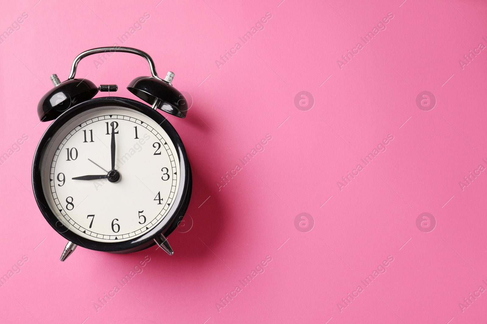Black alarm clock on pink background, top view. Space for text Photo of Black alarm clock on pink background, top view. Space for text