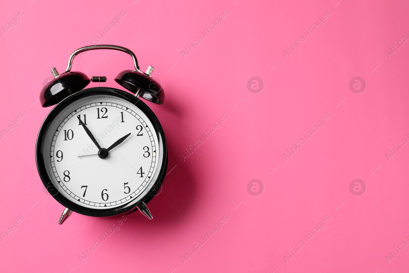 Black alarm clock on pink background, top view. Space for text Photo of Black alarm clock on pink background, top view. Space for text