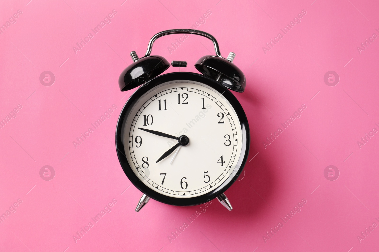 Black alarm clock on pink background, top view Photo of Black alarm clock on pink background, top view