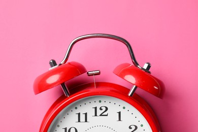 Photo of Red alarm clock on pink background, top view