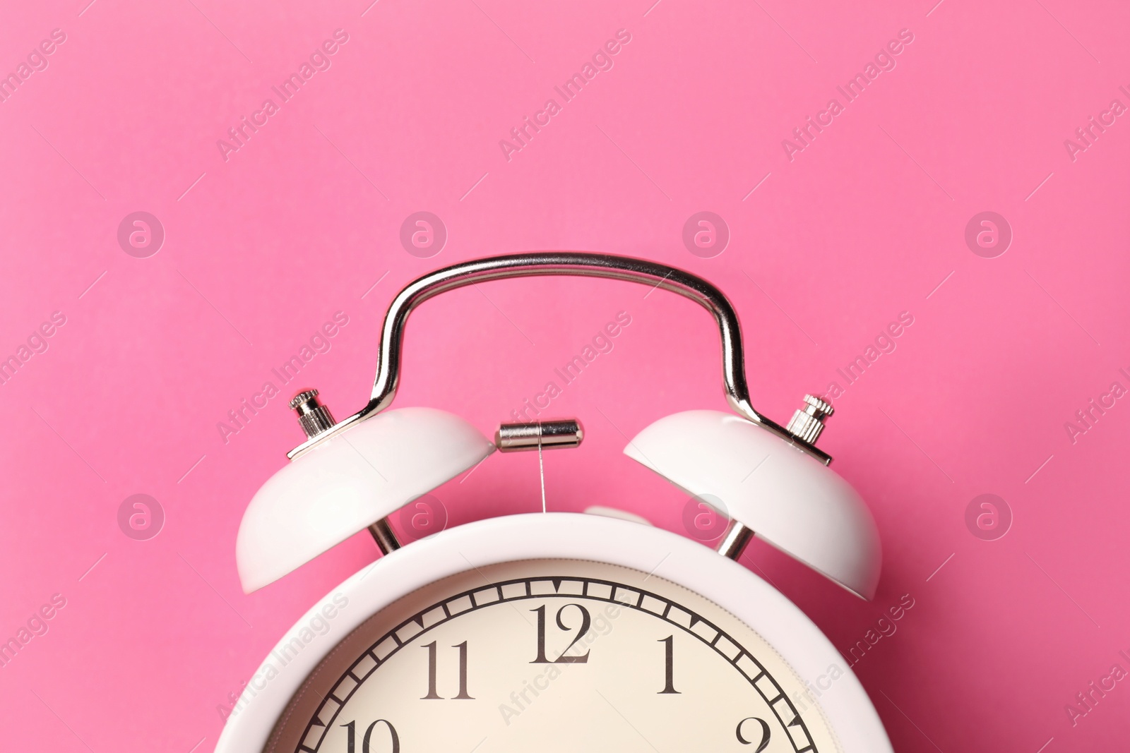 White alarm clock on pink background, top view Photo of White alarm clock on pink background, top view