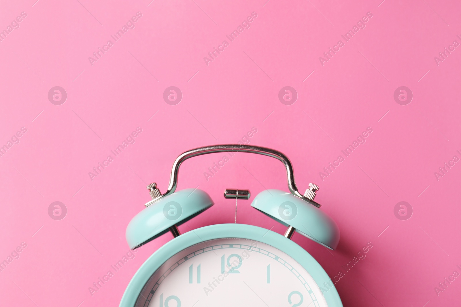 Turquoise alarm clock on pink background, top view. Space for text Photo of Turquoise alarm clock on pink background, top view. Space for text
