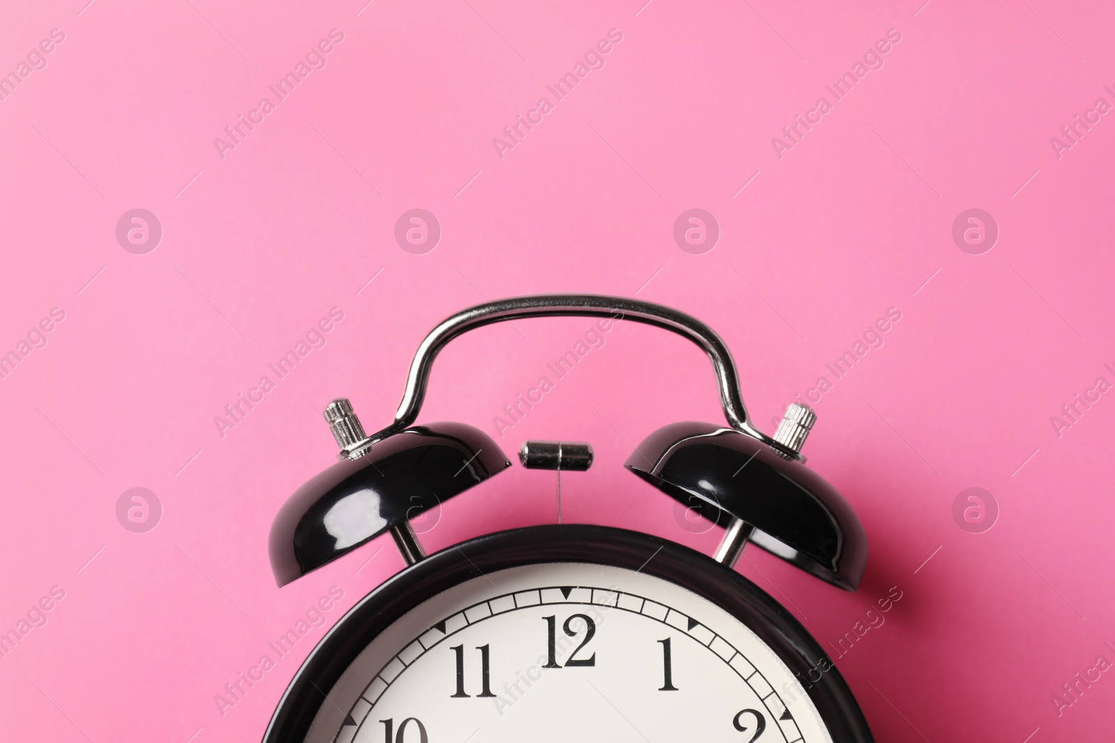 Black alarm clock on pink background, top view Photo of Black alarm clock on pink background, top view