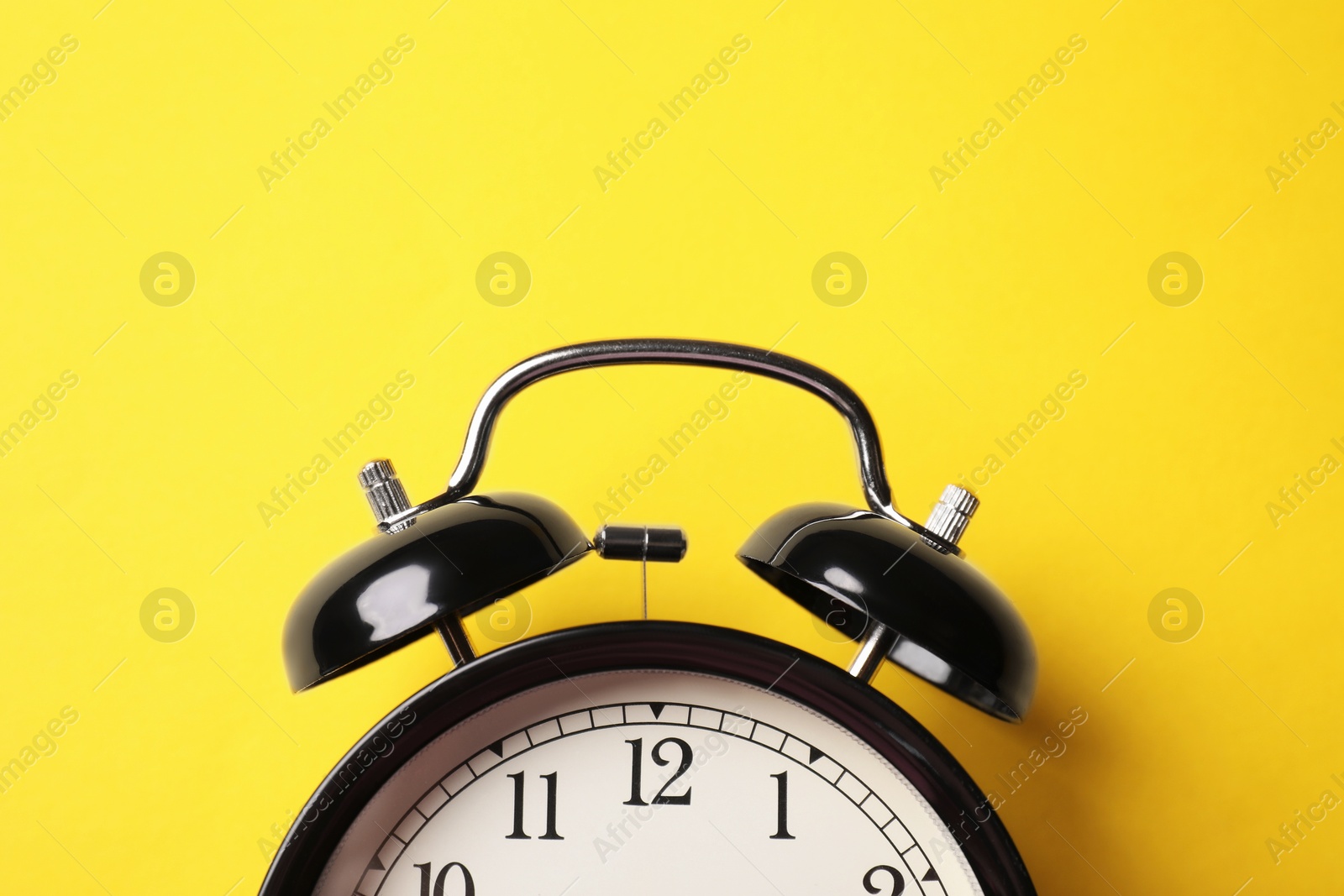 Black alarm clock on yellow background, top view Photo of Black alarm clock on yellow background, top view