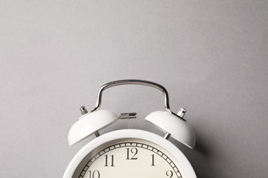 Photo of White alarm clock on grey background, top view. Space for text