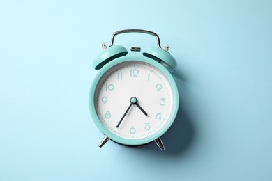 Photo of Turquoise alarm clock on light blue background, top view