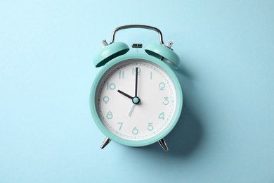 Photo of Turquoise alarm clock on light blue background, top view