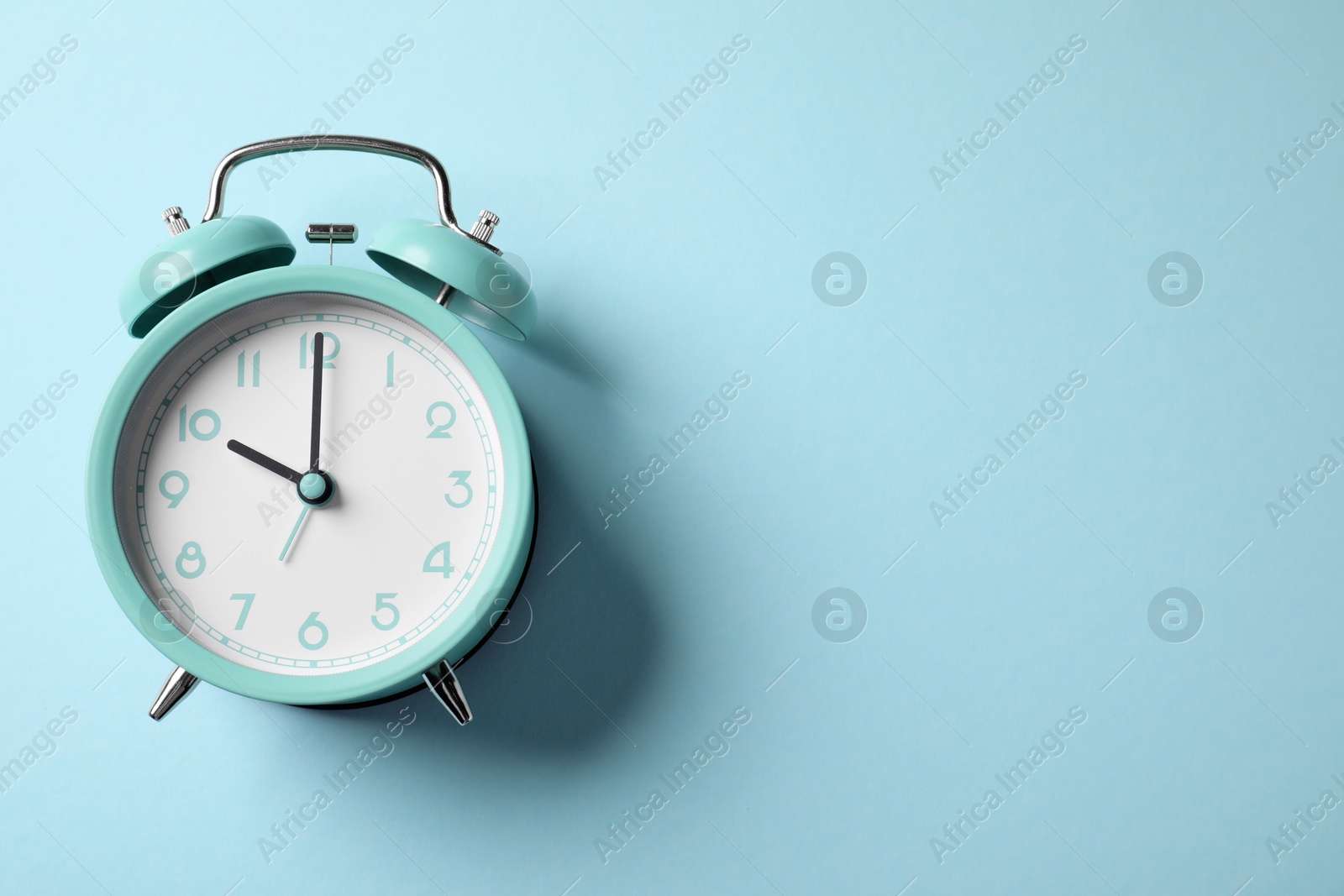 Turquoise alarm clock on light blue background, top view. Space for text Photo of Turquoise alarm clock on light blue background, top view. Space for text
