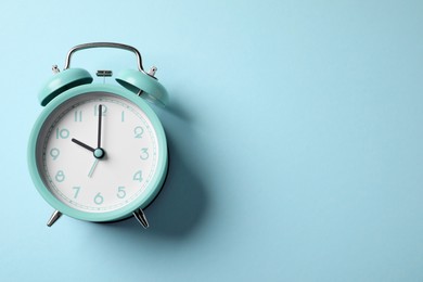 Photo of Turquoise alarm clock on light blue background, top view. Space for text