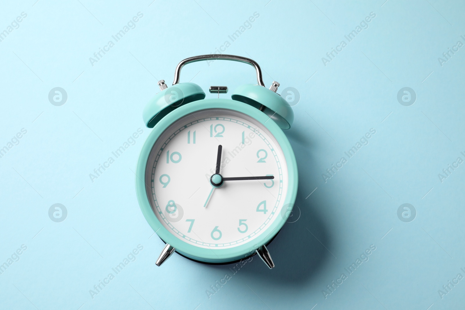 Turquoise alarm clock on light blue background, top view Photo of Turquoise alarm clock on light blue background, top view