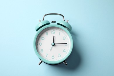 Photo of Turquoise alarm clock on light blue background, top view