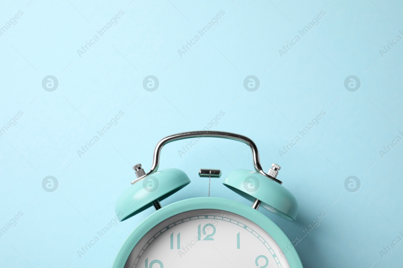 Turquoise alarm clock on light blue background, top view. Space for text Photo of Turquoise alarm clock on light blue background, top view. Space for text