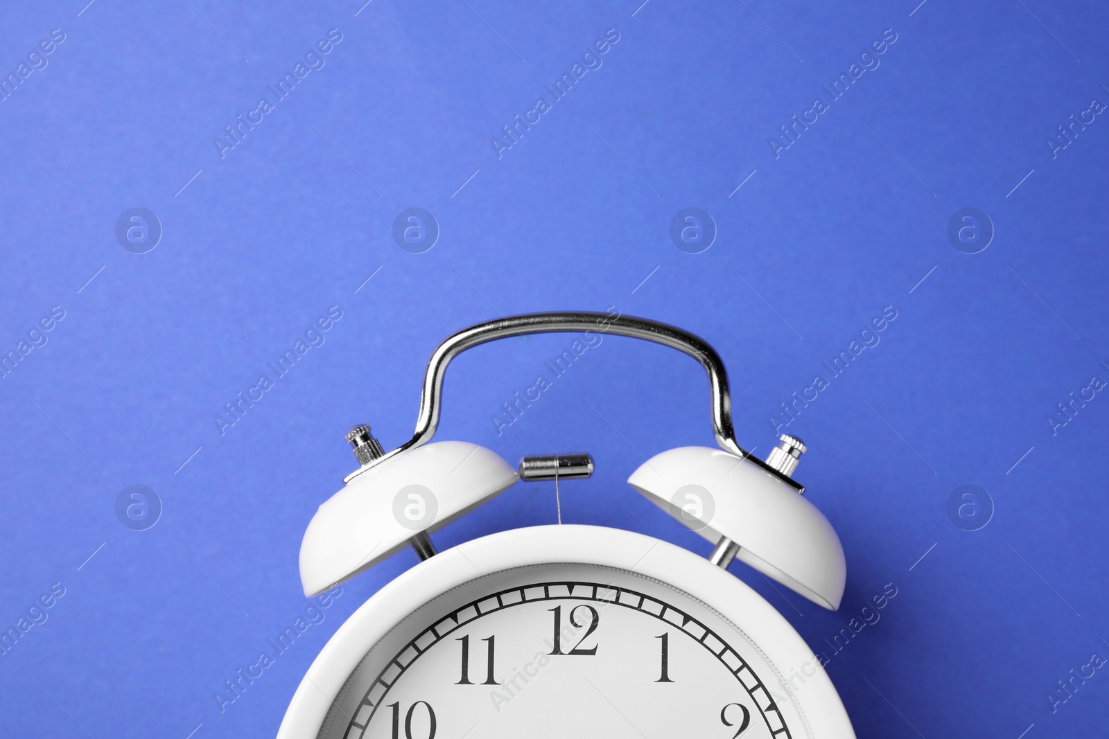 White alarm clock on blue background, top view Photo of White alarm clock on blue background, top view