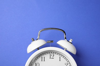 Photo of White alarm clock on blue background, top view