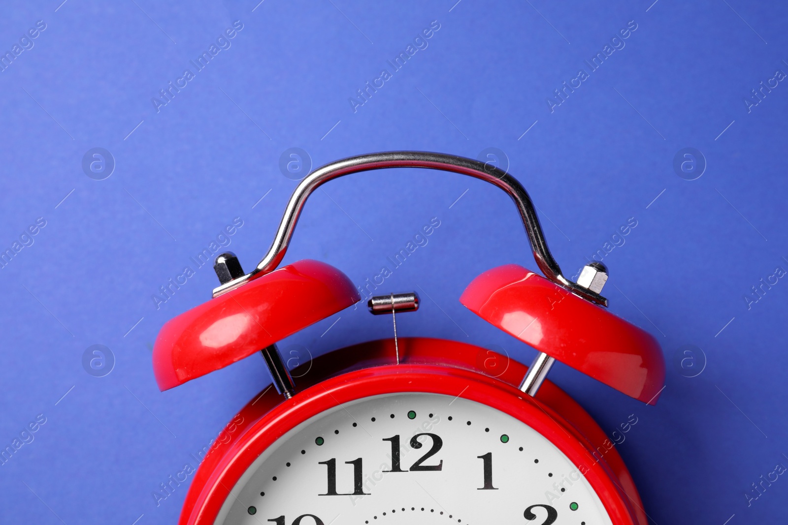 Red alarm clock on blue background, top view Photo of Red alarm clock on blue background, top view