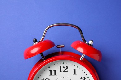 Photo of Red alarm clock on blue background, top view