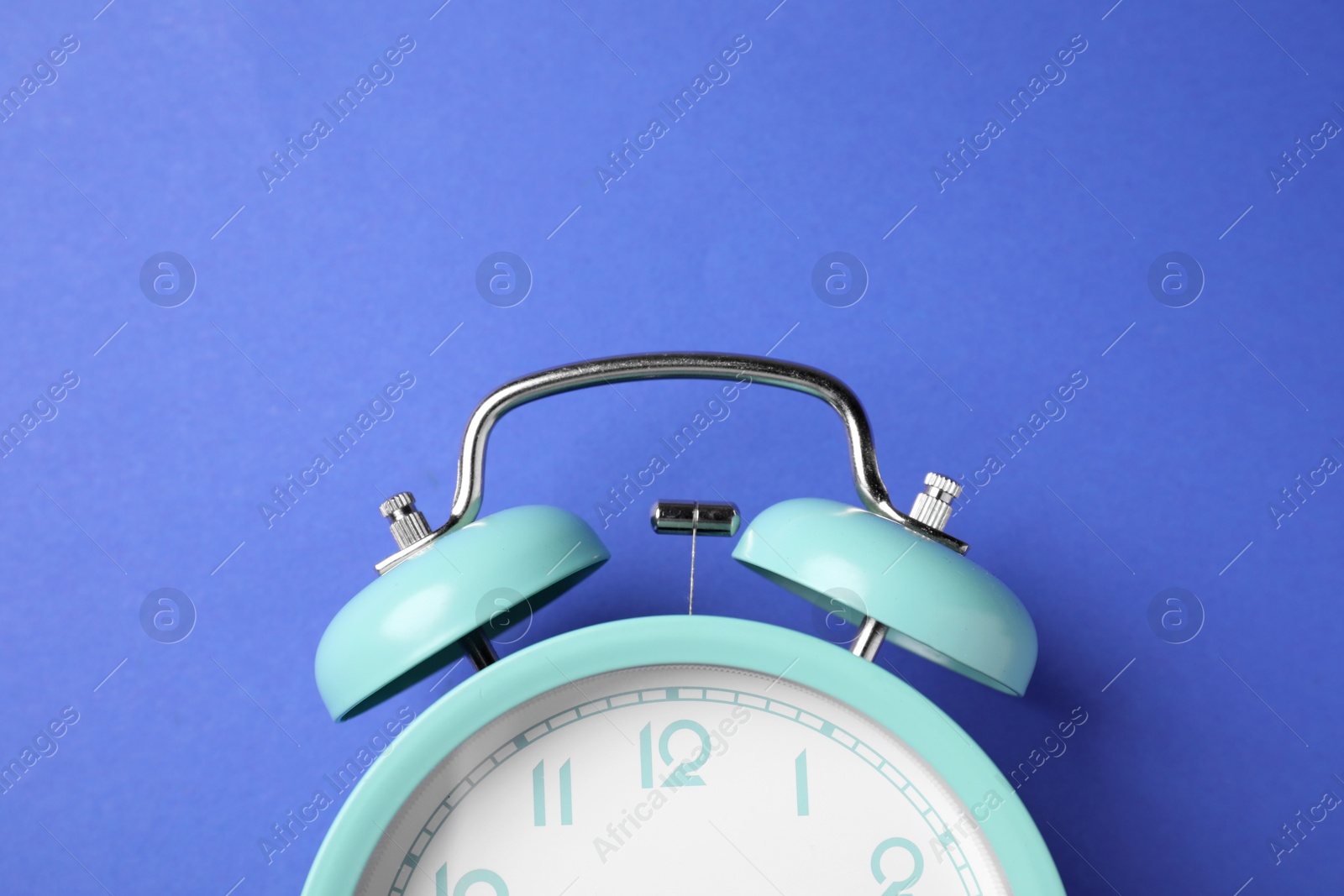 Turquoise alarm clock on blue background, top view Photo of Turquoise alarm clock on blue background, top view