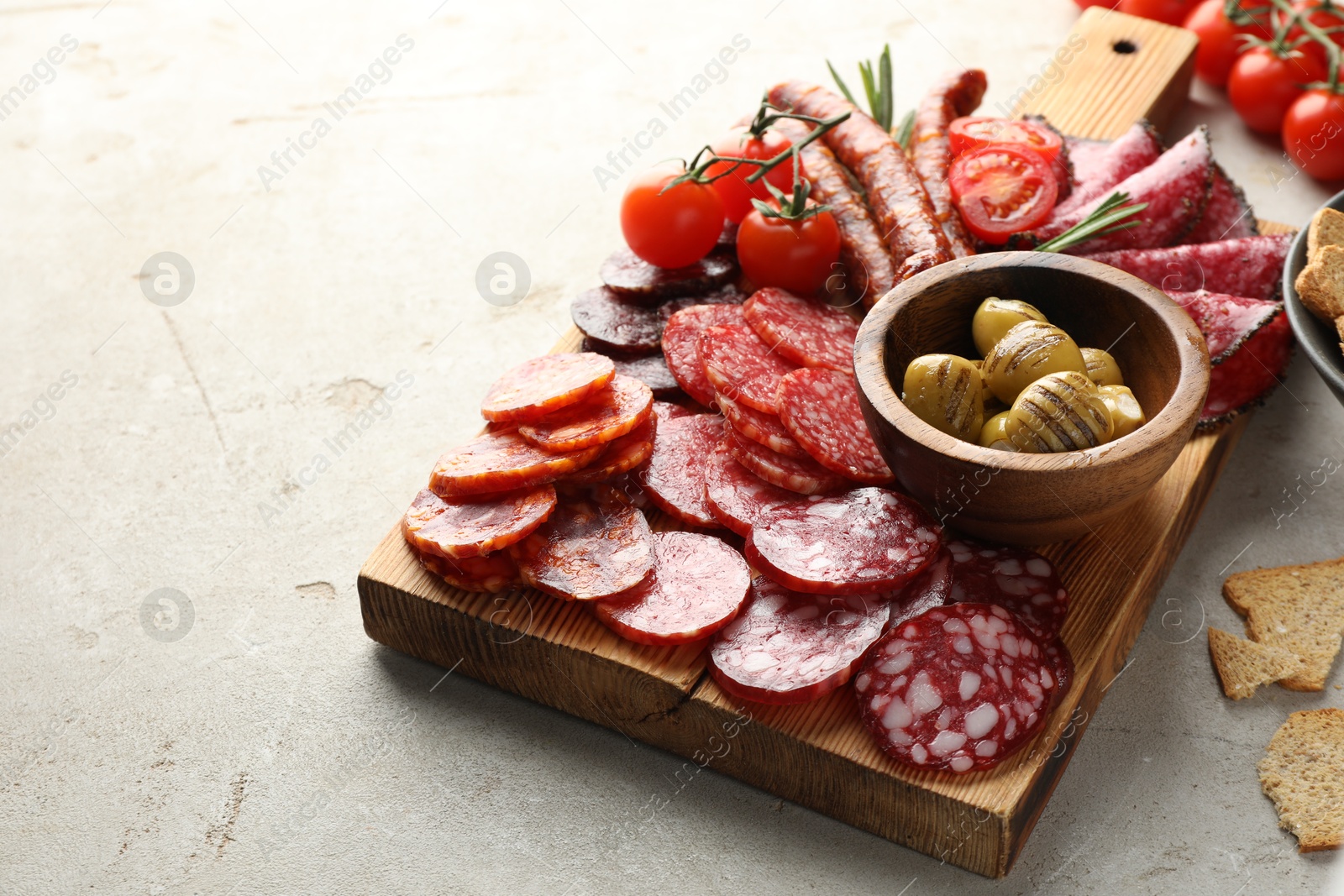 Photo of Different smoked sausages slices served on light table, closeup. Space for text