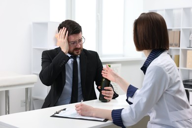 Photo of Alcoholic man having appointment with healthcare specialist in clinic. Addiction treatment