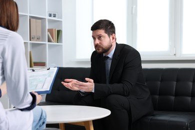 Photo of Alcoholic man having appointment with healthcare specialist in clinic. Addiction treatment