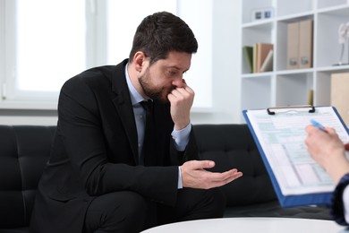 Photo of Alcoholic man having appointment with healthcare specialist in clinic. Addiction treatment