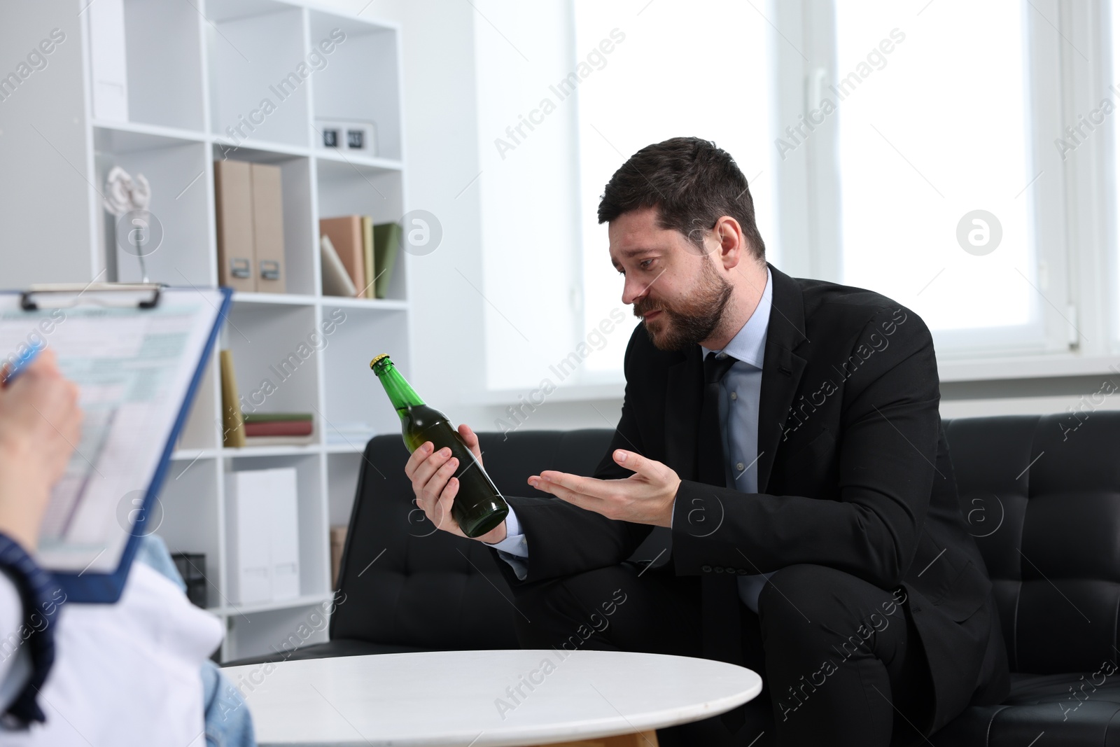 Photo of Alcoholic man having appointment with healthcare specialist in clinic. Addiction treatment